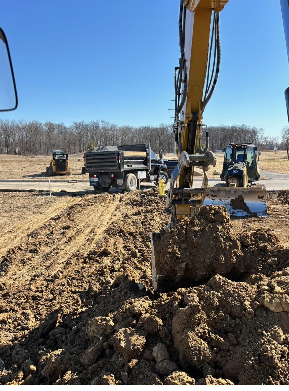 Excavator digging a utility trench with a dozer grading behind it