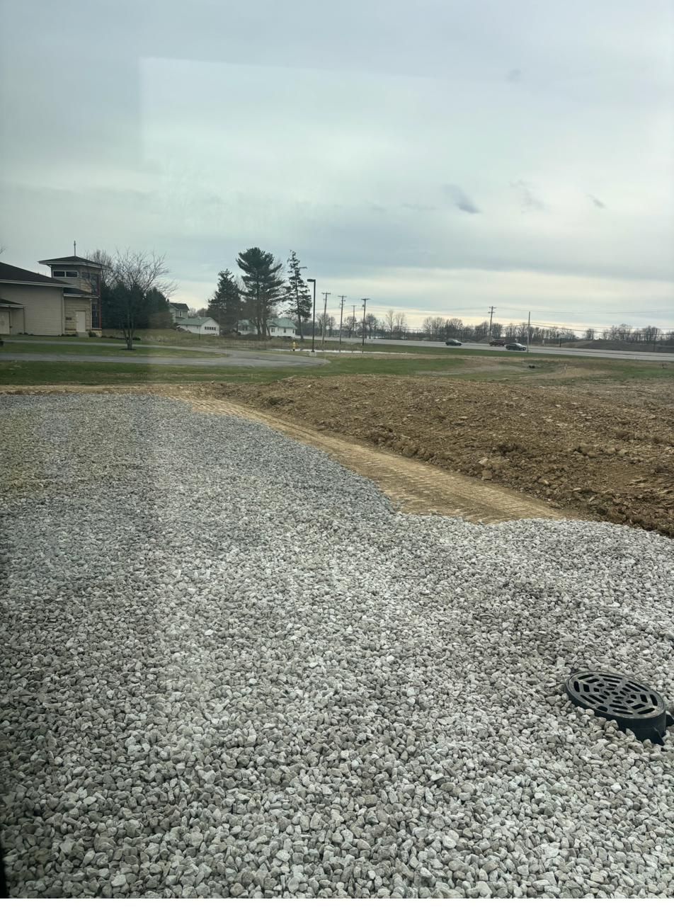 Finished compacted stone pad with drainage structure set flush