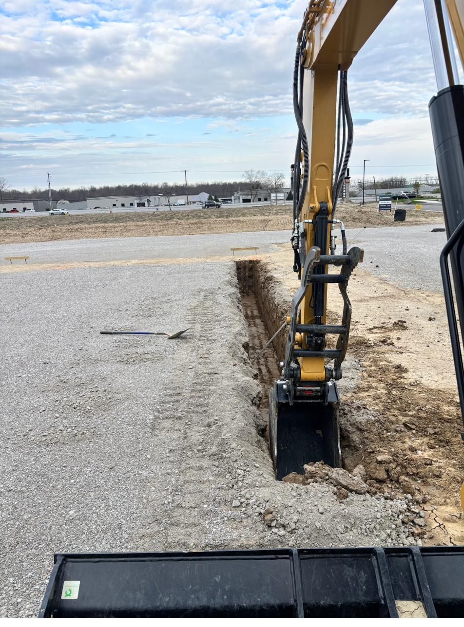 Clean utility trench cut through a compacted stone building pad