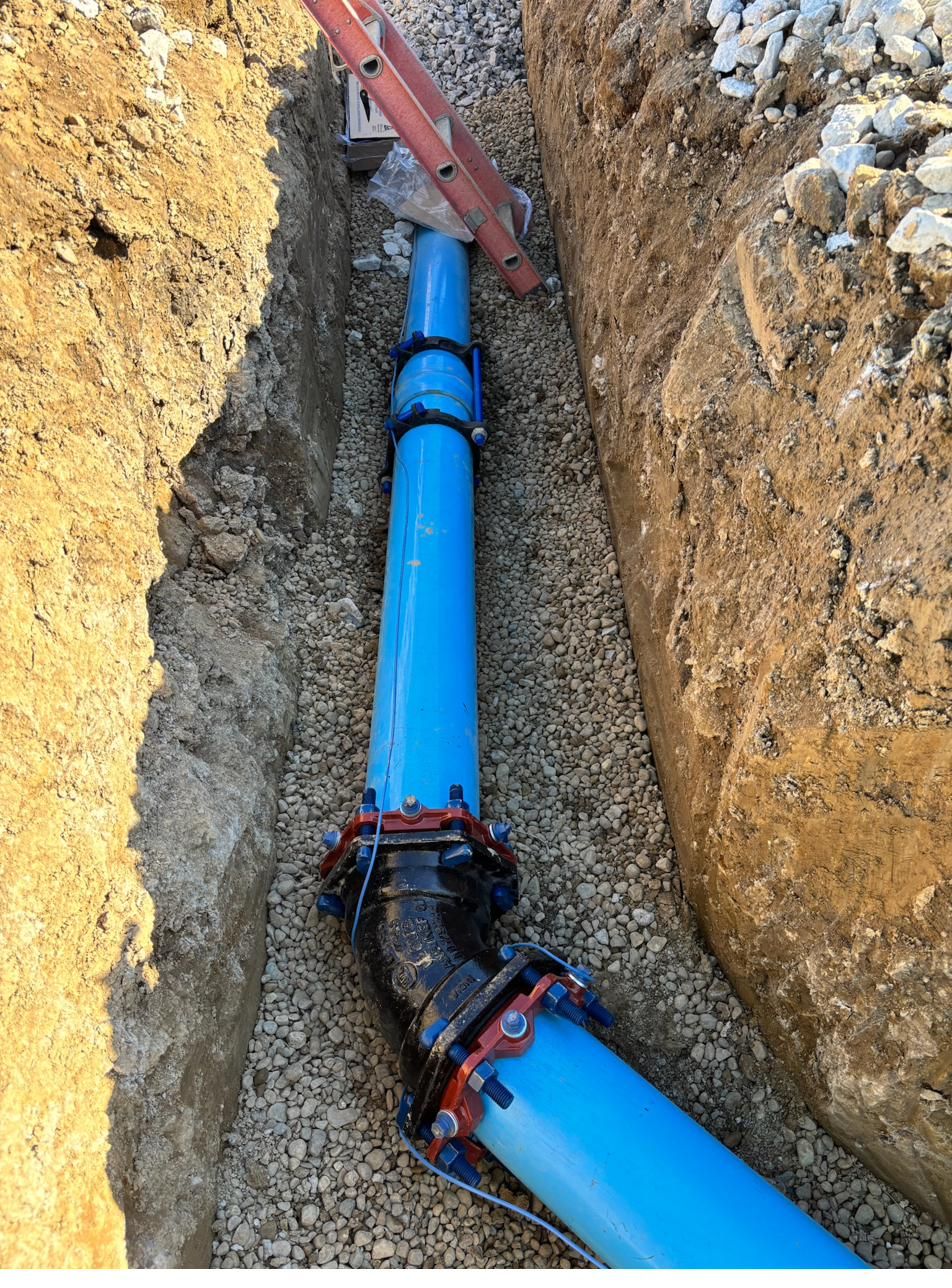 Blue C900 water main with restrained fittings installed in an open trench