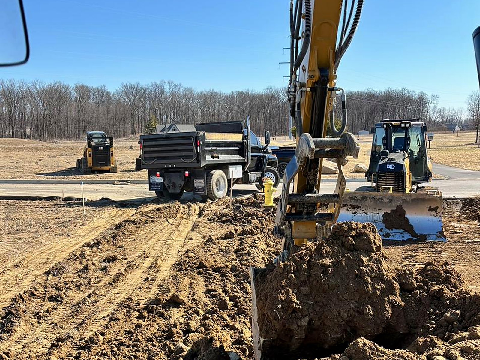 Excavator trenching with dozer grading behind on a commercial site
