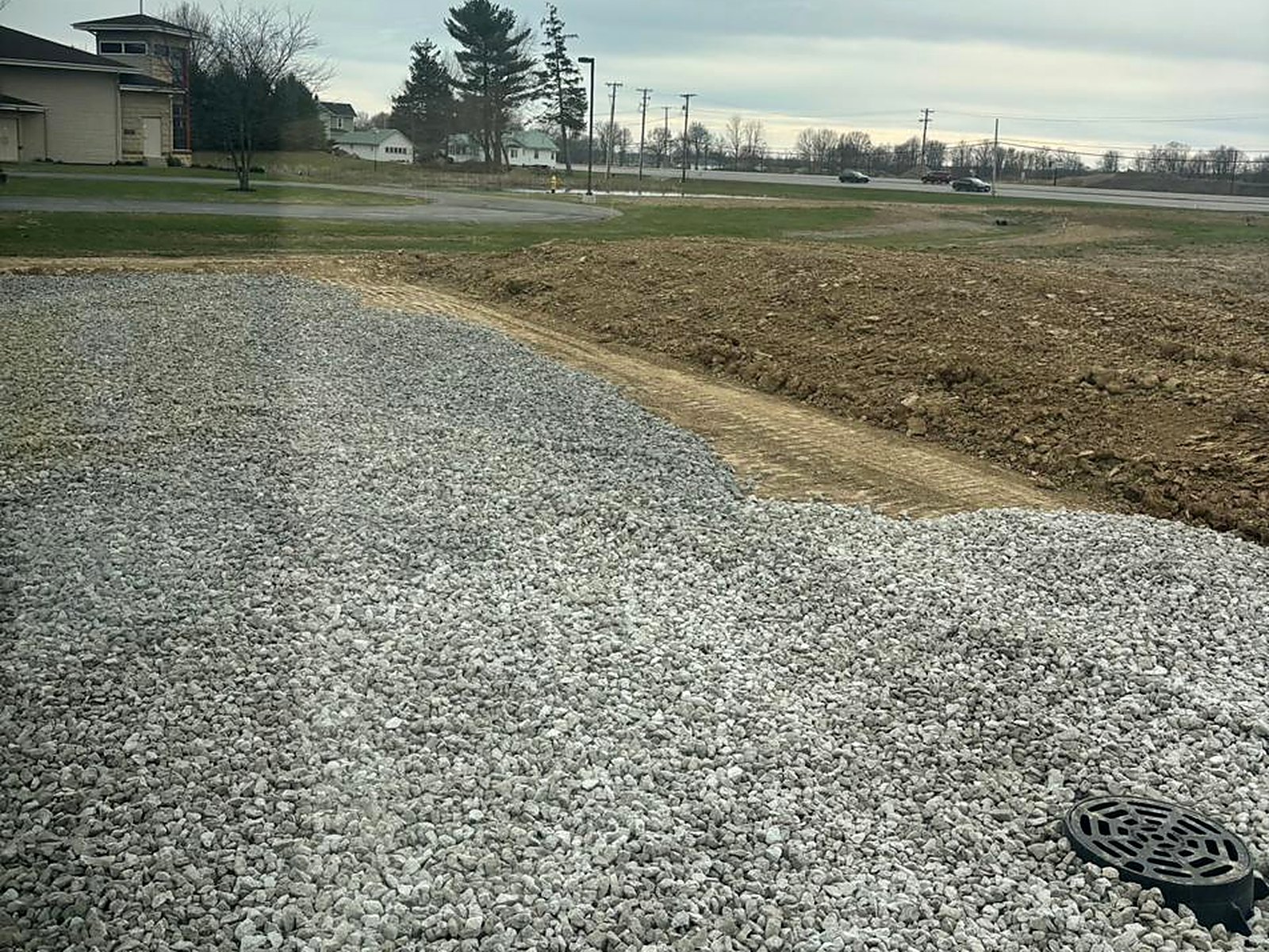 Compacted stone building pad with drainage structure set flush