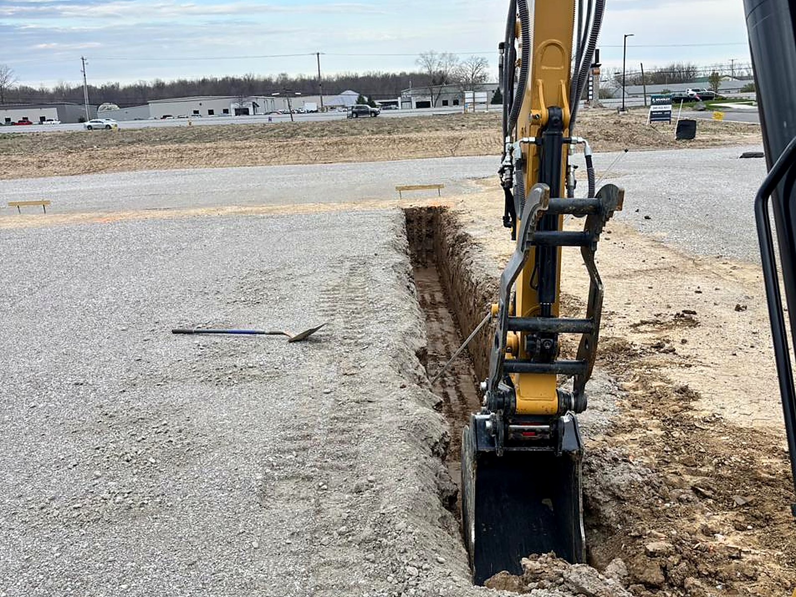 Clean utility trench cut through a compacted stone building pad